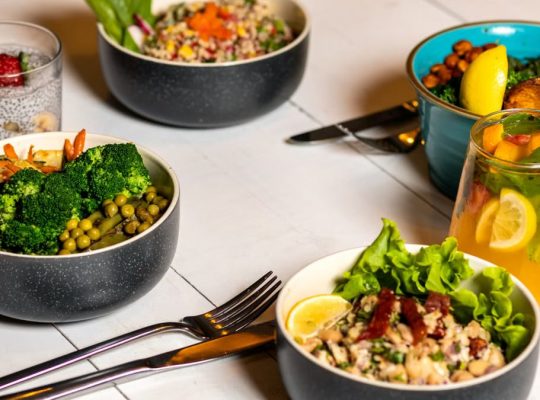 A vibrant assortment of healthy bowls and drinks showcasing fresh ingredients like broccoli and citrus.