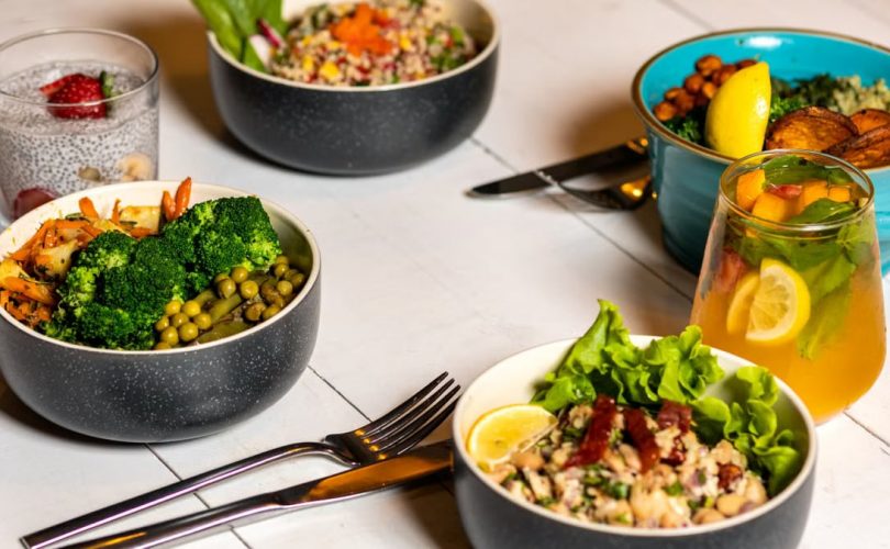 A vibrant assortment of healthy bowls and drinks showcasing fresh ingredients like broccoli and citrus.