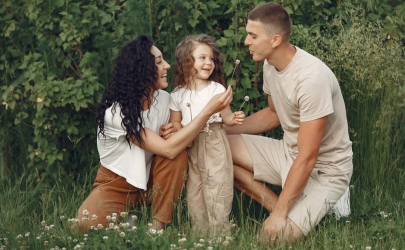 A joyful family enjoying time together in a lush green meadow, capturing love and bonding.